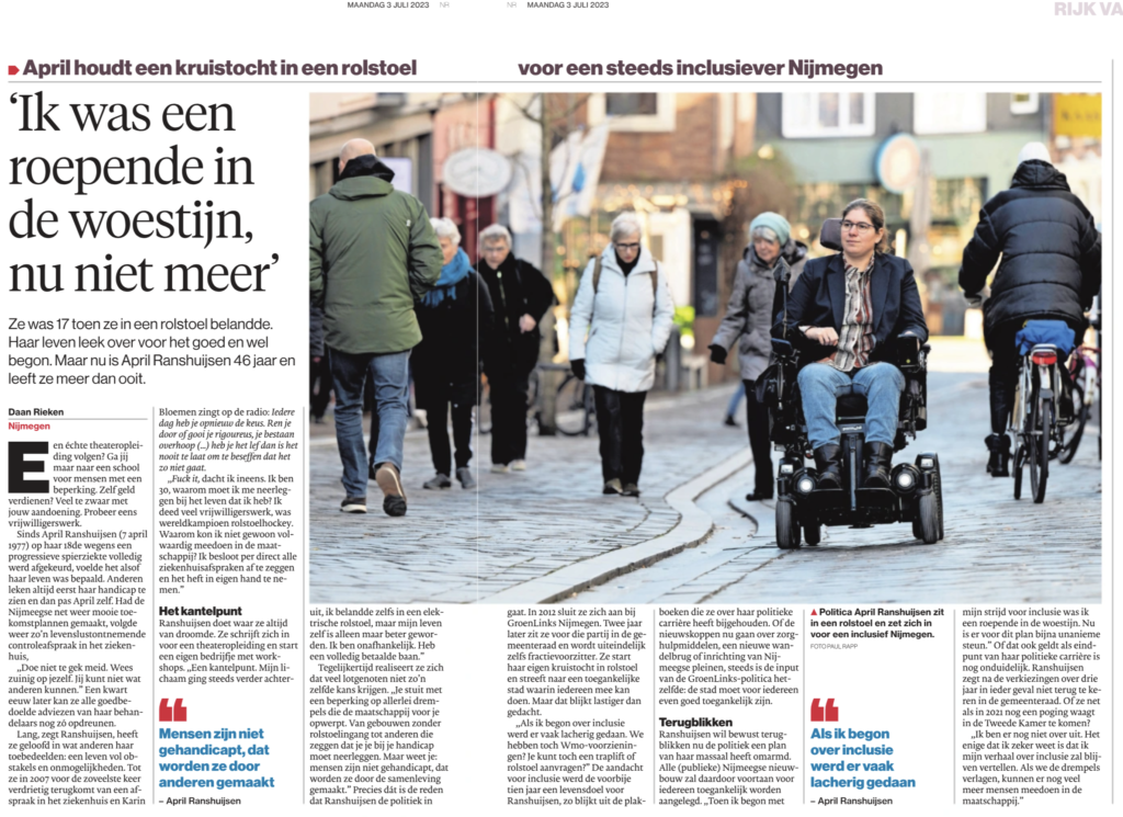 Foto van een groot krantenartikel met een foto van April rijdend in haar rolstoel in een winkelstraat. De kop luidt: ik was een roepende in de woestijn, nu niet meer'.